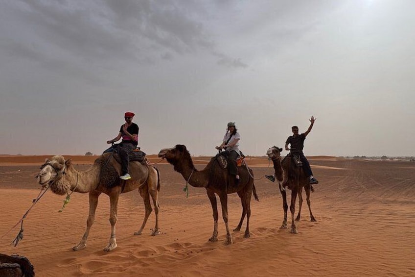 Three camels with riders in a desert landscape. 3