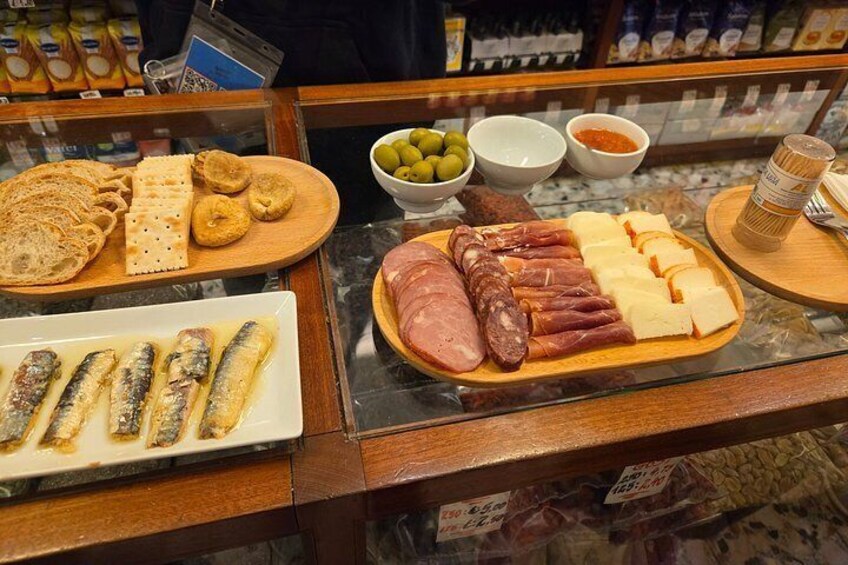 A deli counter with various meats, cheeses, and crackers. 2
