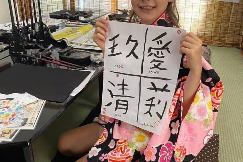 A person holding a paper with Japanese characters, sitting at a desk with papers and a printer. 5