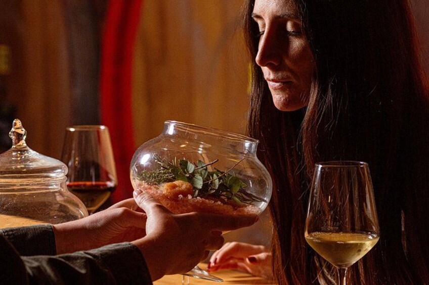 A person holding a glass bowl with food and a wine glass on a table. 5