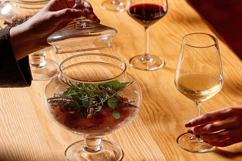 A wooden table with a glass bowl containing a salad and a wine glass filled with white wine. 4
