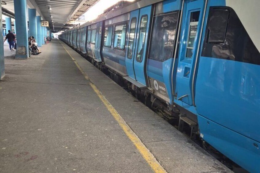 A blue train at a station platform with a yellow safety line. 3