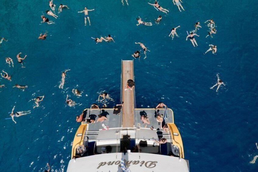 A boat with people swimming in the water around it. 3