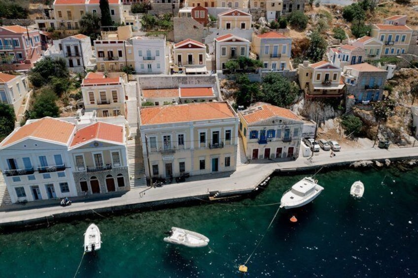 A coastal town with buildings along the waterfront, boats docked, and a clear view of the sea. 2