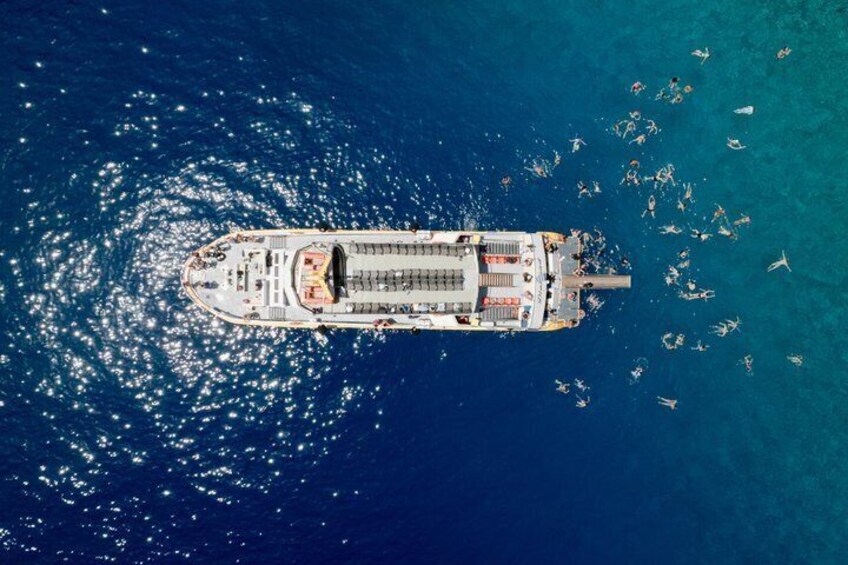 An aerial view of a cruise ship with passengers swimming in the water around it. 5