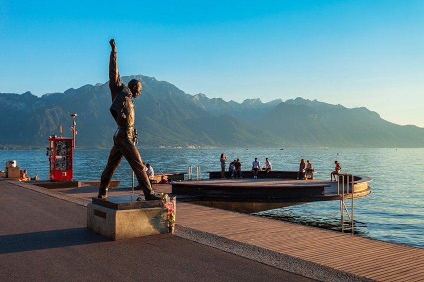 A statue on a pier, a lake, and mountains in the background. 5