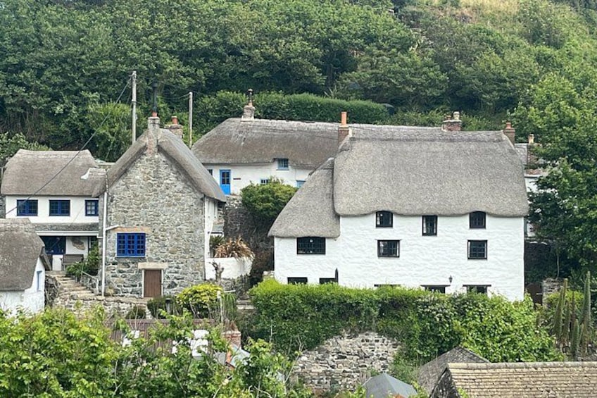 A coastal village with stone houses, thatched roofs, and lush greenery. 5