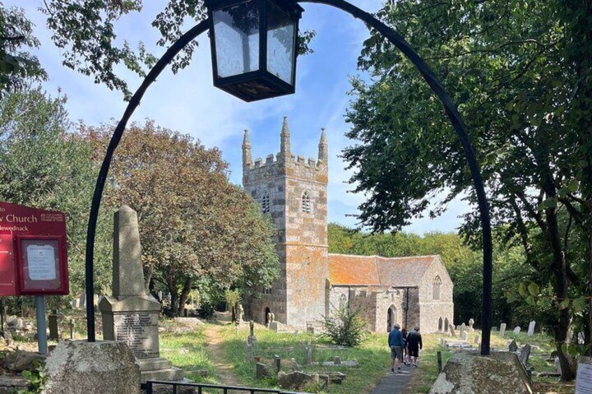 A church with a tall tower, a stone monument, and a signpost in a cemetery. 5