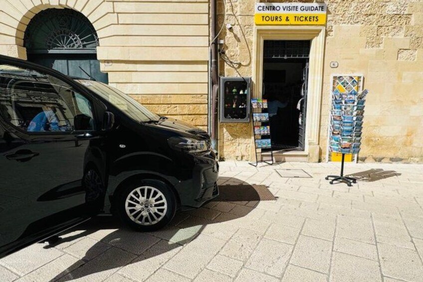 A black car parked in front of a building with a sign for Centro Visit Guide Tours & Tickets. 2
