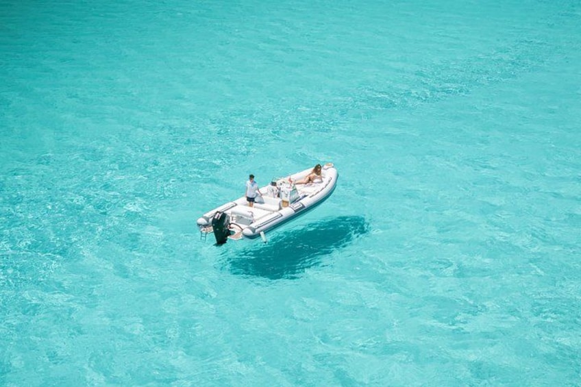 A small inflatable boat on clear turquoise water. 1