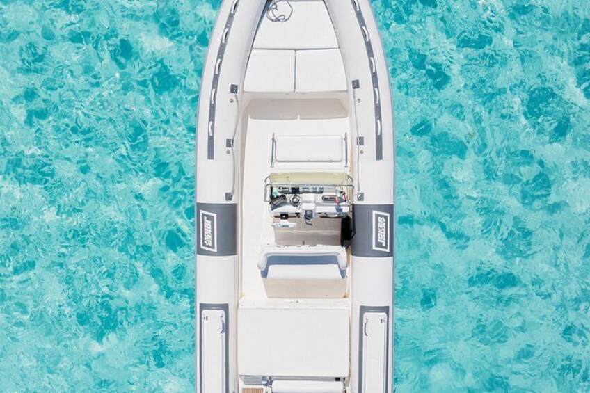 A white boat with a cabin and a small deck area, floating on turquoise water. 2