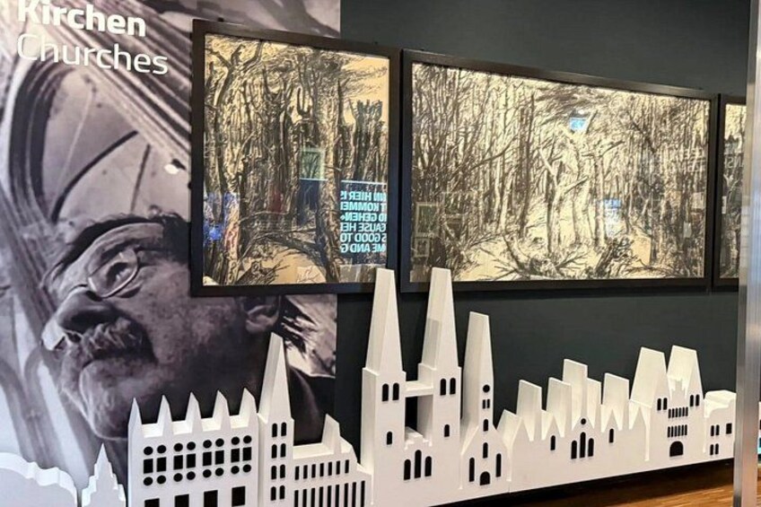 A wall with framed artwork, a model of a cityscape, and a partial view of a person's face. 4