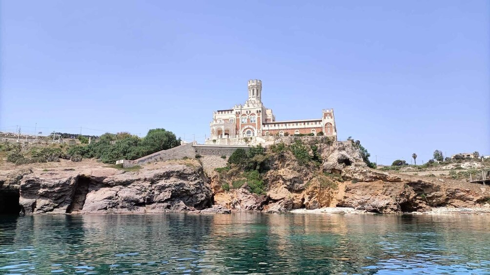 A historic building with a tower on a rocky cliff overlooking a body of water. 3