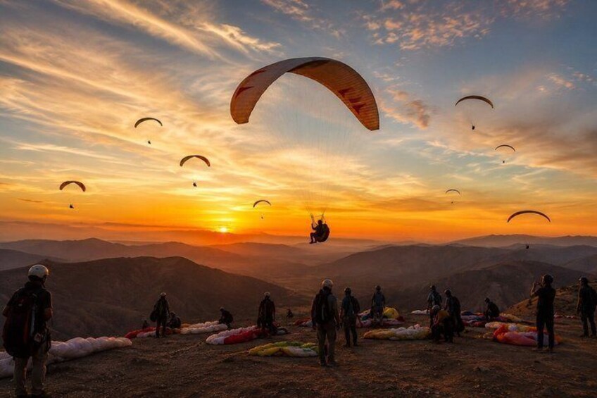 Paragliders flying over a mountainous landscape at sunset. 1
