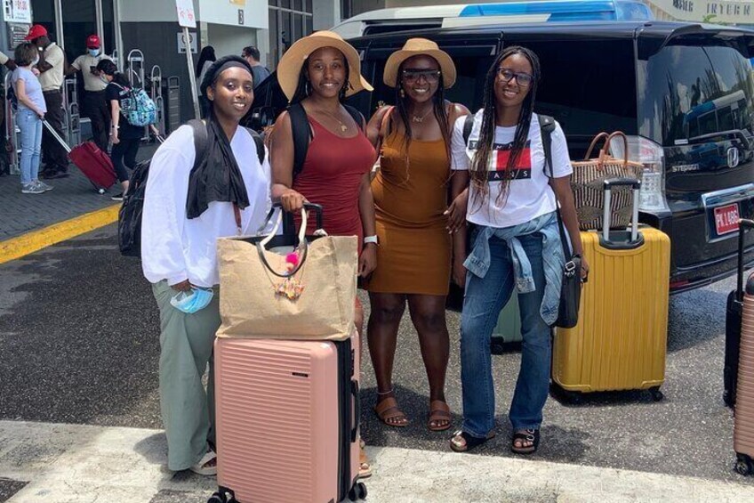 Three people standing in front of a black van with luggage. 3