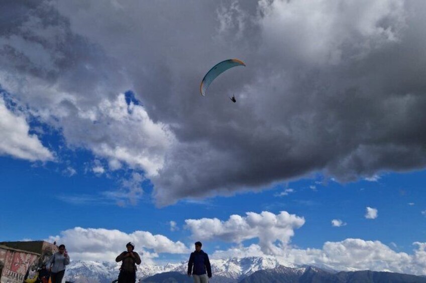 A person paragliding above a mountain range with a partly cloudy sky. 4