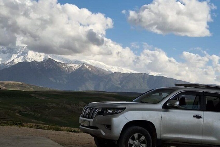 A silver SUV parked with a mountain range in the background. 5
