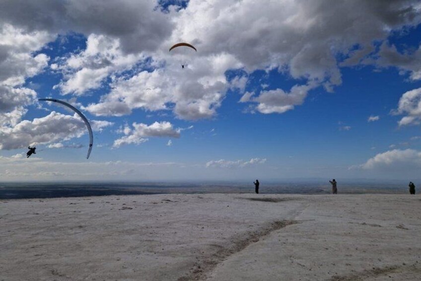 A beach with people and paragliders. 3