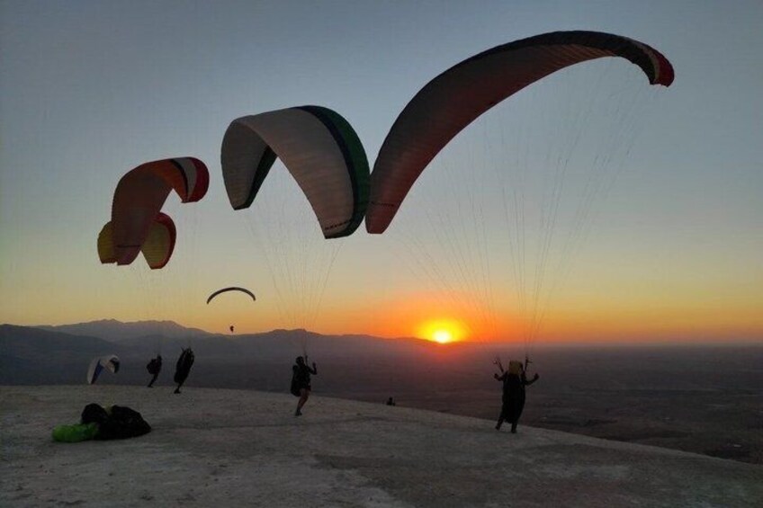 A group of paragliders with parachutes above a desert landscape at sunset. 5