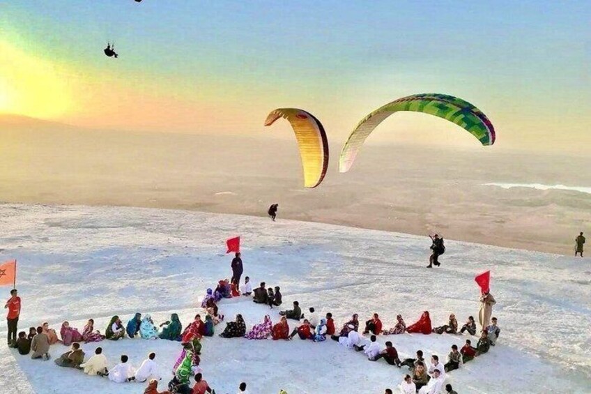 A group of people on a snowy mountain with kites and flags. 3