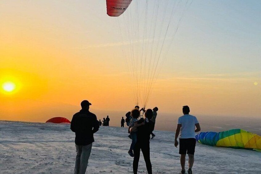 A group of people on a beach at sunset with kites. 1