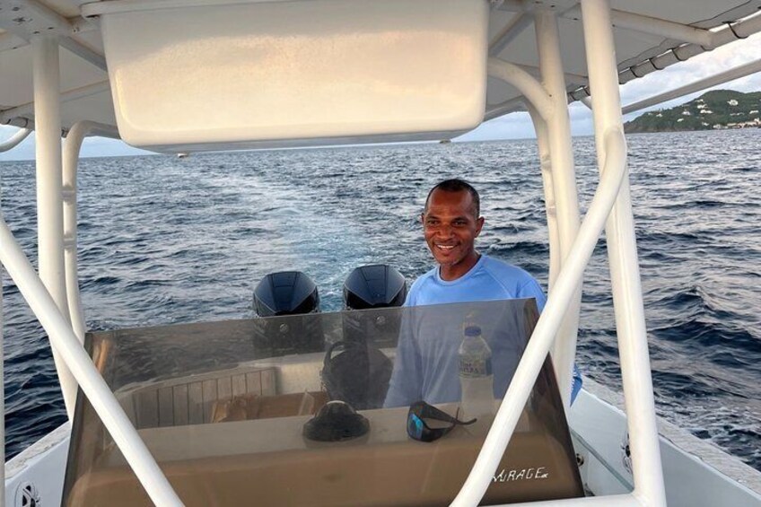 A person on a boat with a water bottle and a life jacket on the deck. 2