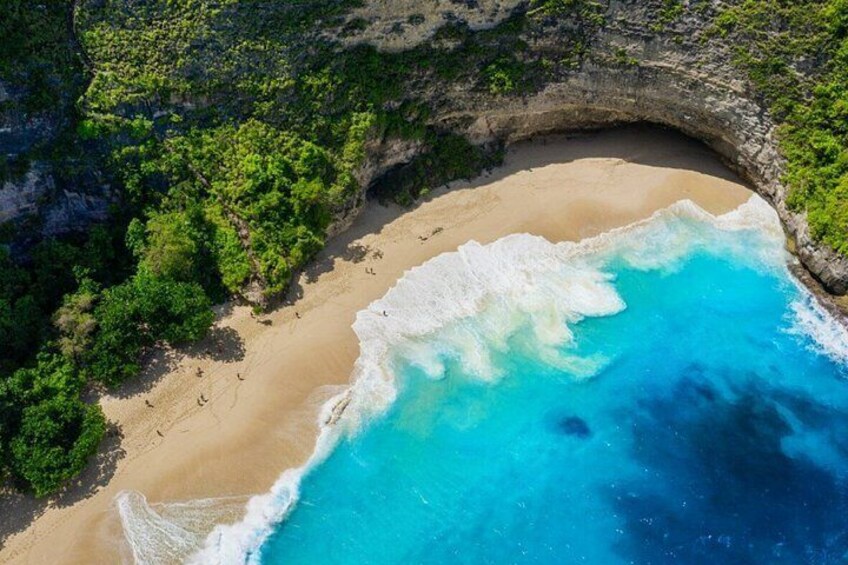 A beach with clear turquoise water, a sandy shore, and lush greenery. 1