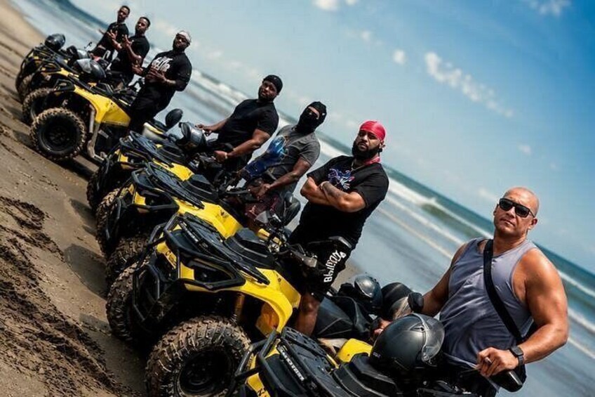 A group of people on all-terrain vehicles on a beach. 1