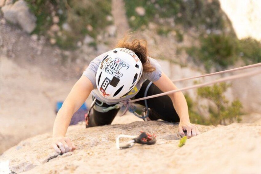 A person climbing a rocky terrain with a helmet and climbing gear. 5