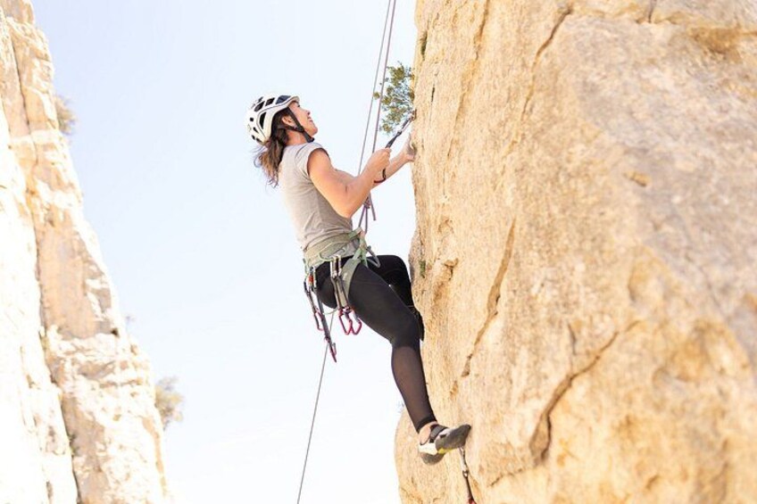 A person rock climbing on a large rock face. 2