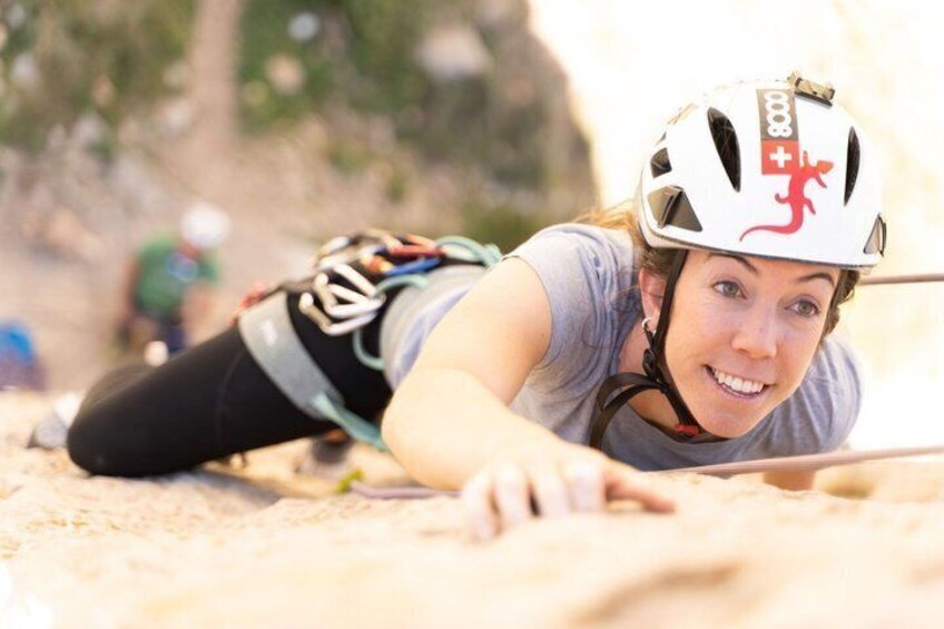 A person in a helmet and climbing gear, engaged in rock climbing. 3