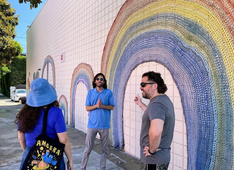 Three people standing in front of a colorful mosaic wall. 2