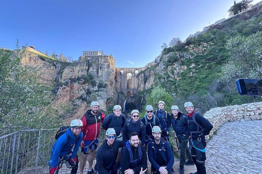 A group of people on a rocky path with a cliff and a building in the background. 1
