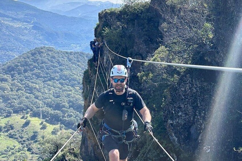 A person rappelling down a cliff with a rope, surrounded by a mountainous landscape. 3