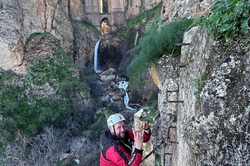A person climbing a rocky mountain path with a backpack and a helmet. 4