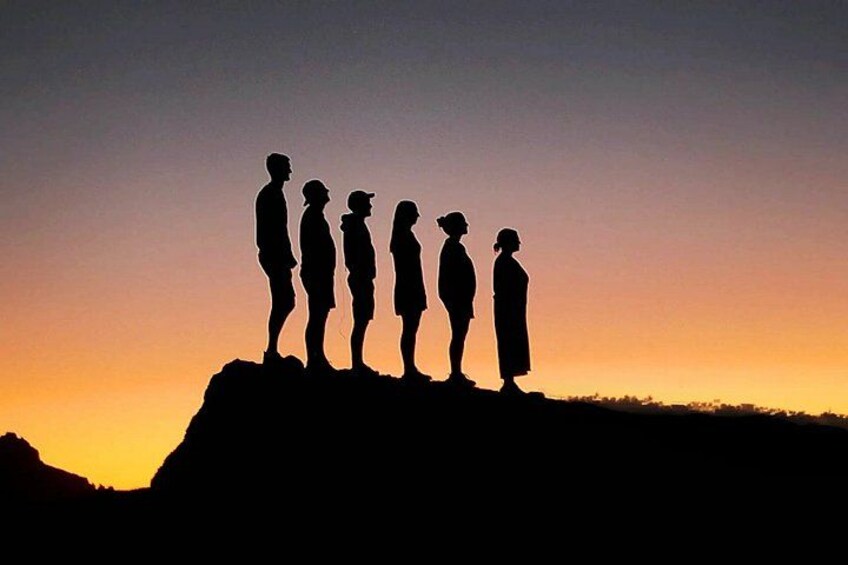 Silhouettes of people standing on a hill during sunset. 3