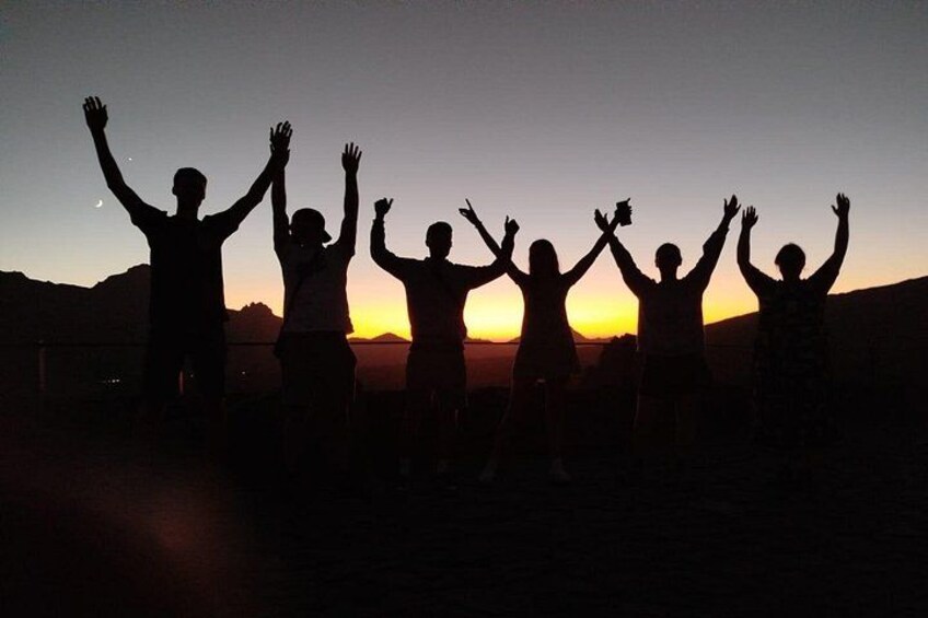 Silhouettes of people with raised arms against a sunset. 2
