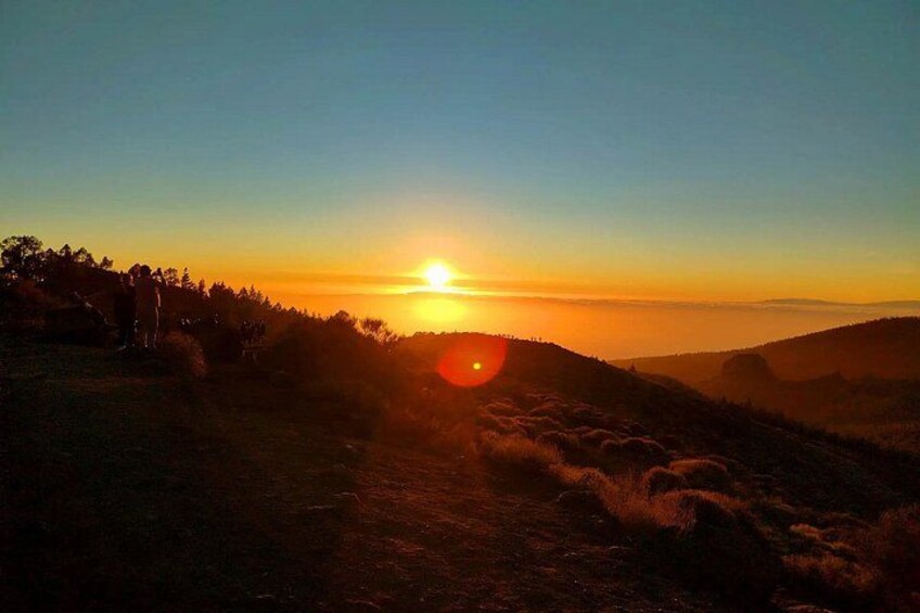 A sunset over a hilly landscape with a path leading towards the sun. 2