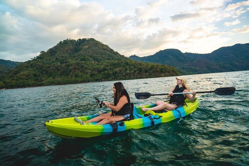 Two people kayaking on a lake with mountains in the background. 2