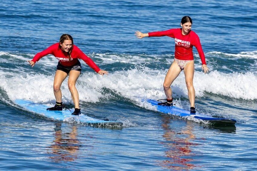 Two people surfing on blue boards in the ocean. 3