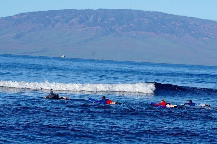 A group of people surfing on the ocean with a mountain range in the background. 5