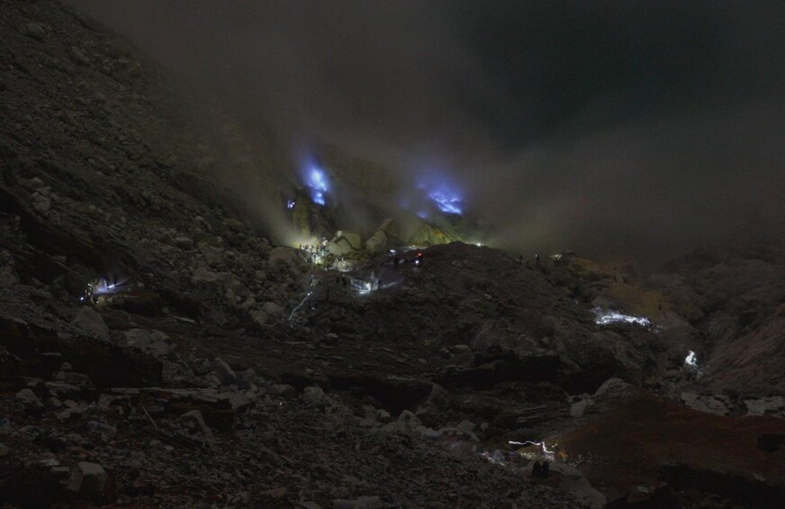 A rocky landscape at night with illuminated areas and a misty atmosphere. 3