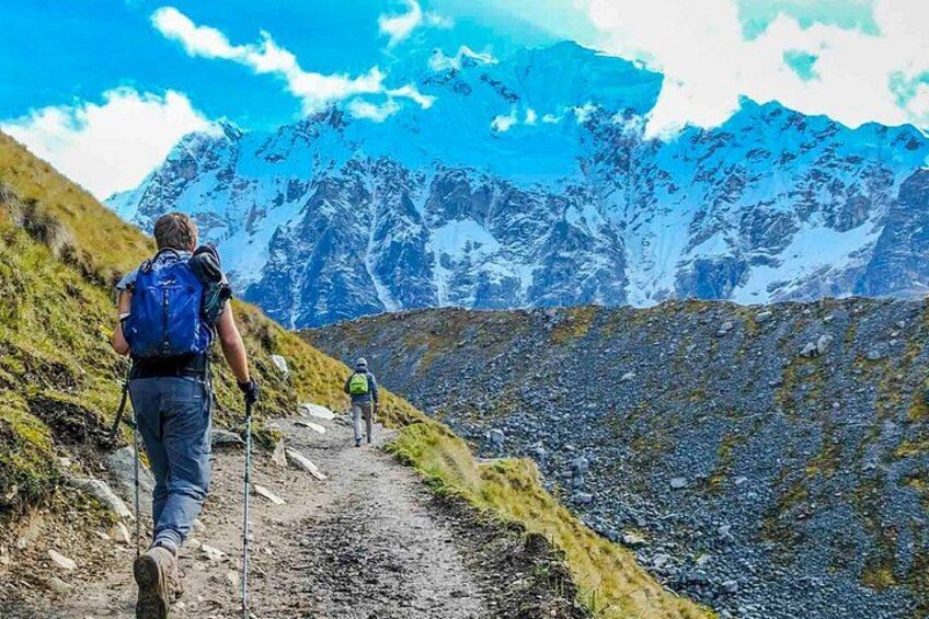 Hikers on a mountain trail with snow-capped peaks in the background. 1