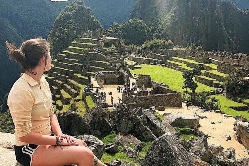 A person sitting on rocks overlooking Machu Picchu ruins. 2