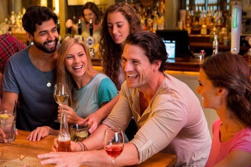 A group of people sitting at a bar with drinks. 4