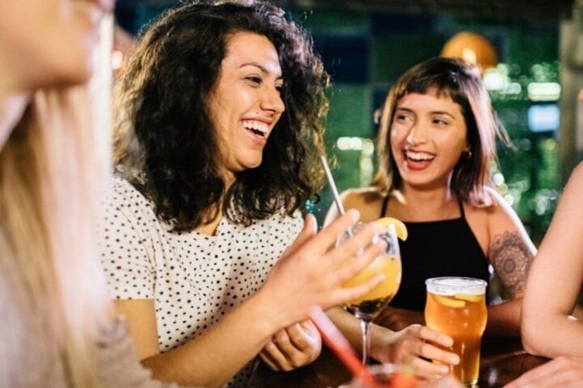 A group of people sitting at a table, holding drinks. 1