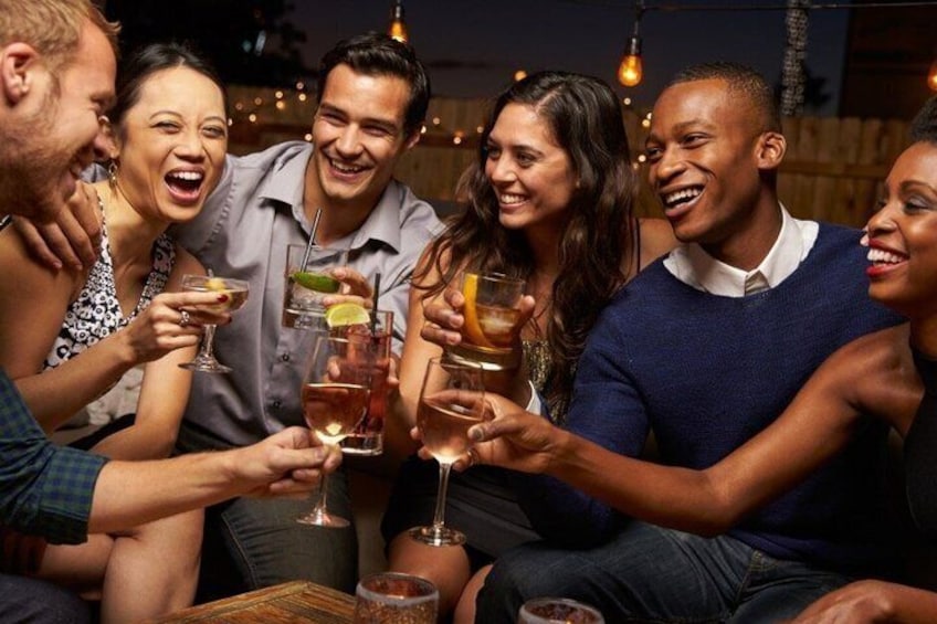 A group of people toasting with drinks in a dimly lit indoor setting. 2