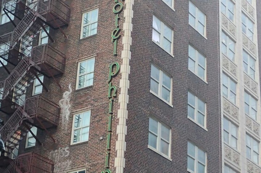 A multi-story brick building with fire escapes and a sign reading 'Hotel Philadelphia.' 4