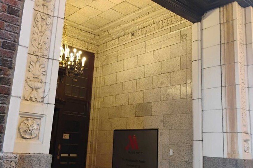 A building entrance with a brick column, a chandelier, and a sign with a red logo. 3