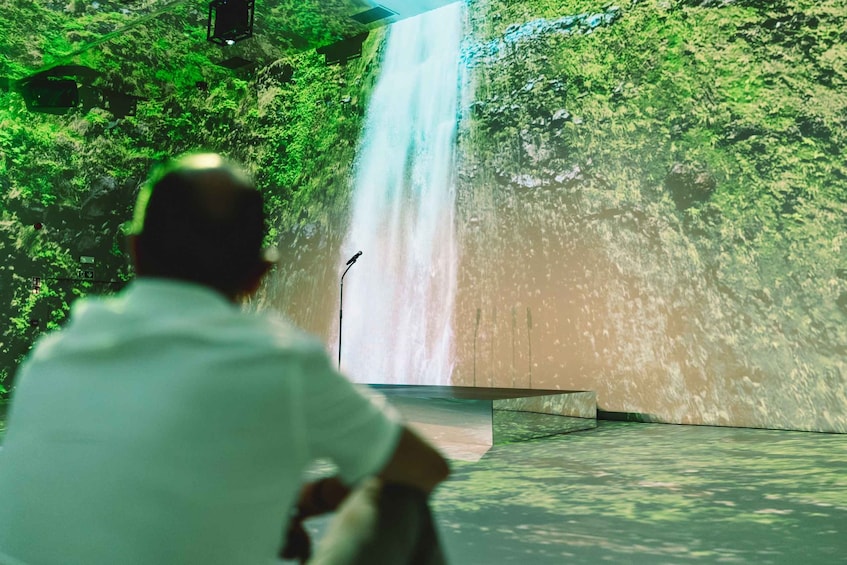 A person sitting in front of a waterfall with a microphone stand. 2